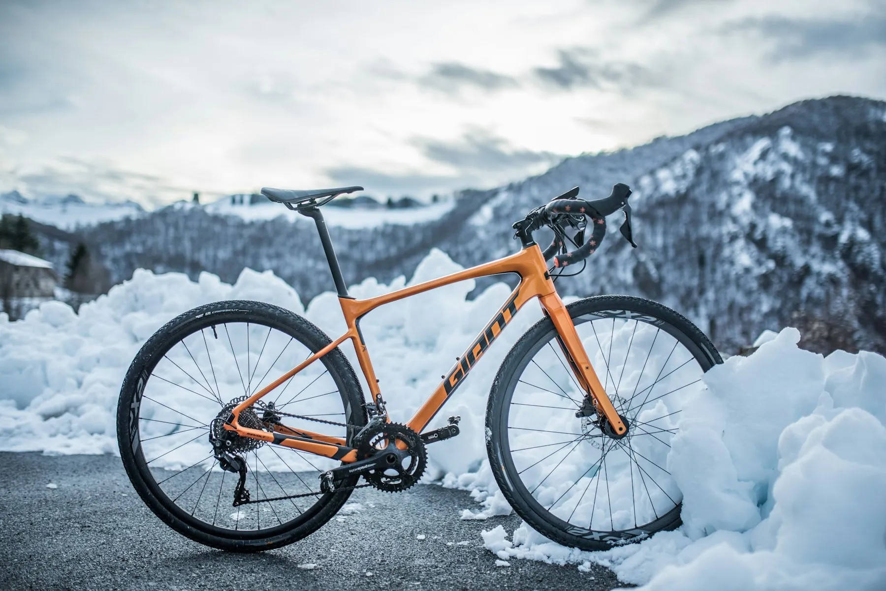 An orange gravel bike by snowy mountains